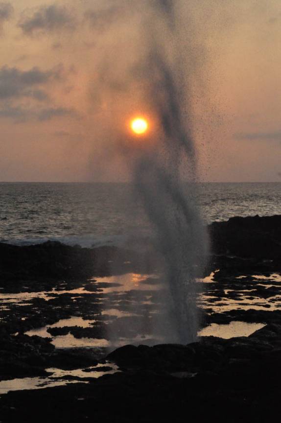 O sol de põe por detrás de um blow hole na costa sul de Kauai, no Havaí